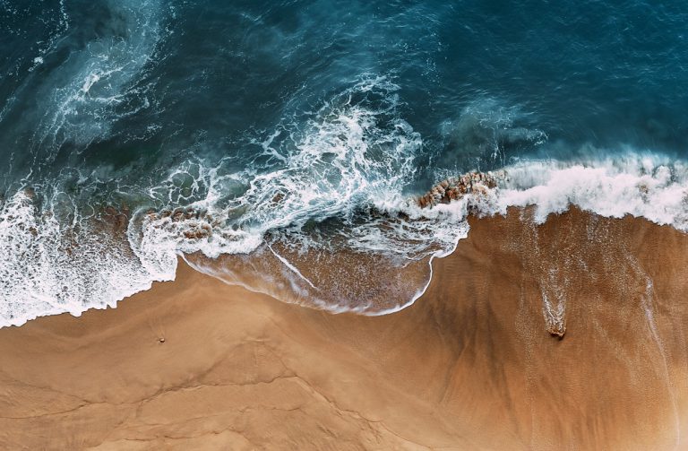 Beautiful sandy beach with blue ocean, vertical view. Blue sea and sandy beach of Nusa penida Bali Indonesia. Lonely sandy beach with beautiful waves. Beautiful seascape background. Copy space